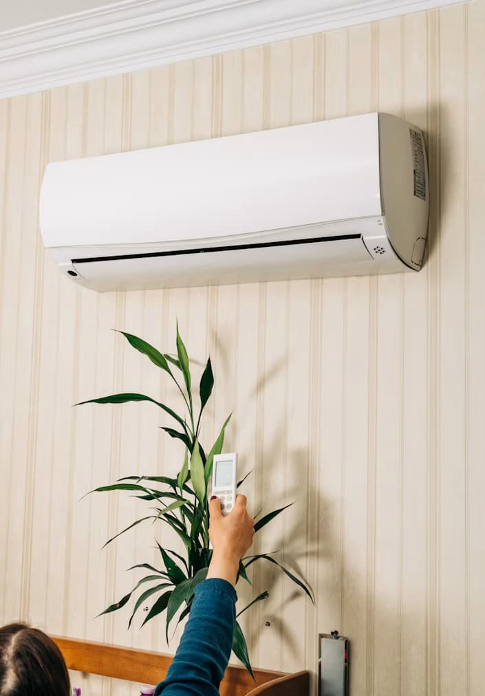 A hand using a remote to set a comfortable temperature
