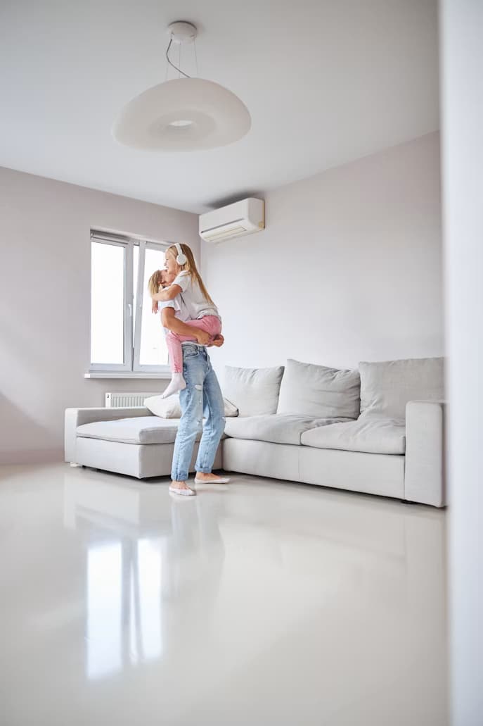 A family relaxing in a bright, comfortable room cooled by a wall air-conditioning unit